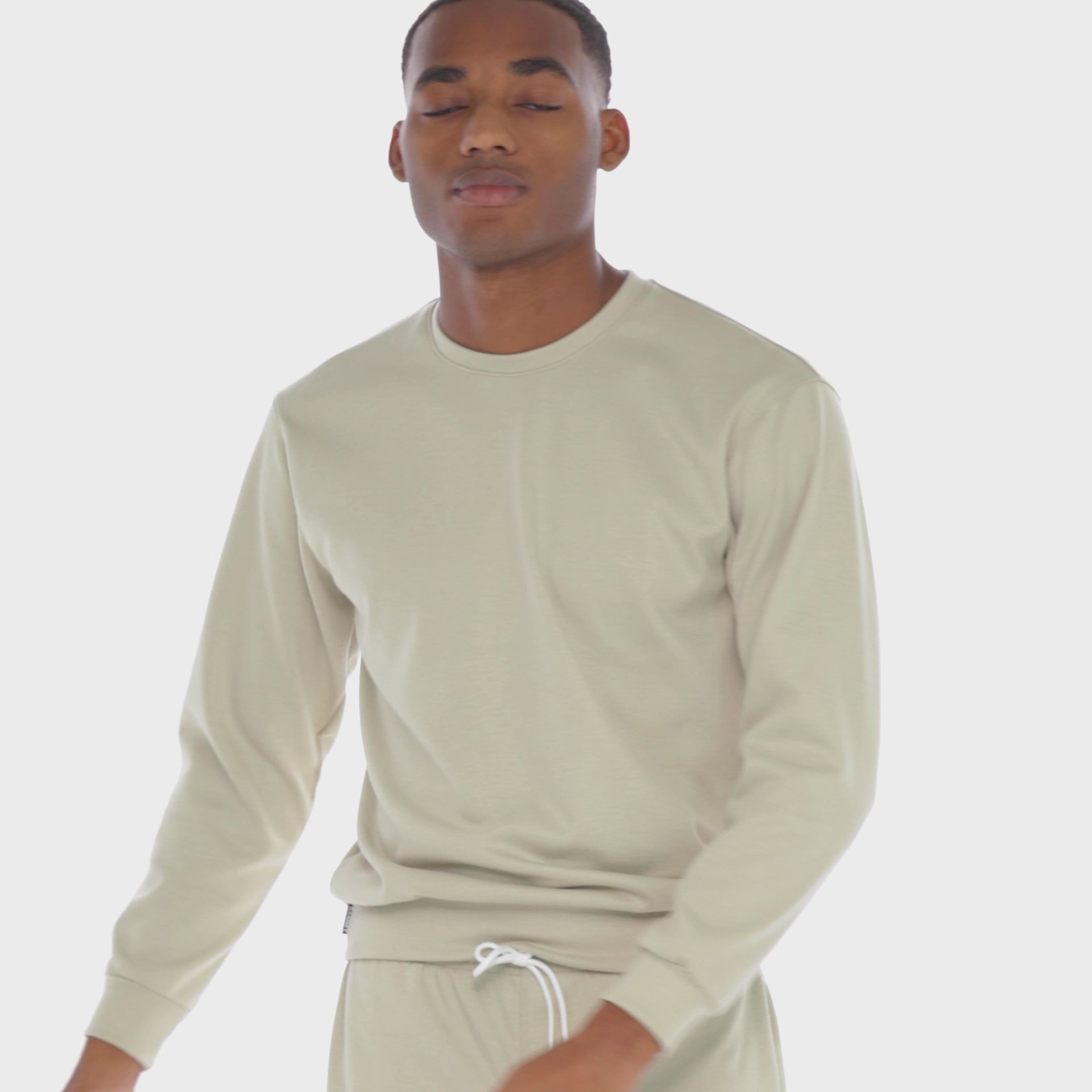 A WHITE WALL VIDEO OF A MALE MODEL WEARING THE SAMMY SHOP UNISEX SAND EVERYDAY CREW SWEATSHIRT