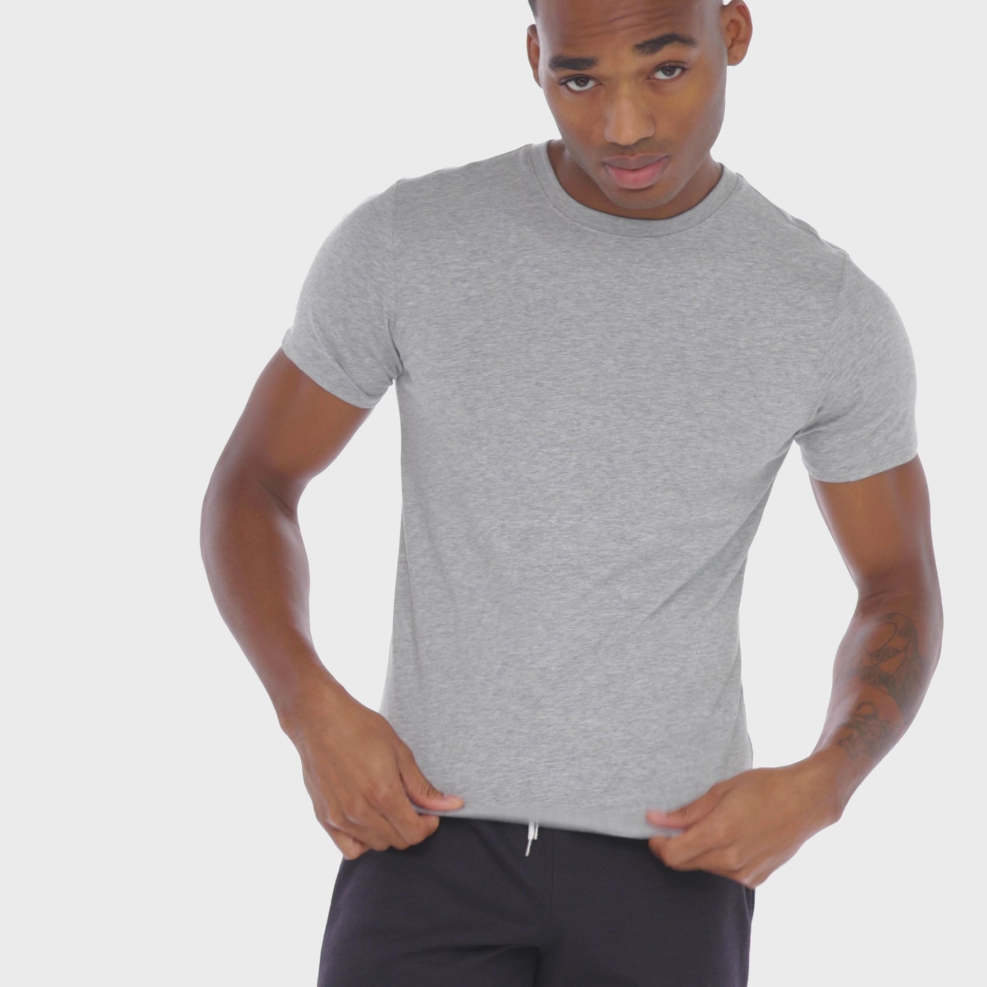 A WHITE WALL VIDEO OF A MALE MODEL WEARING A SAMMY SHOP UNISEX GRAY EVERYDAY T-SHIRT